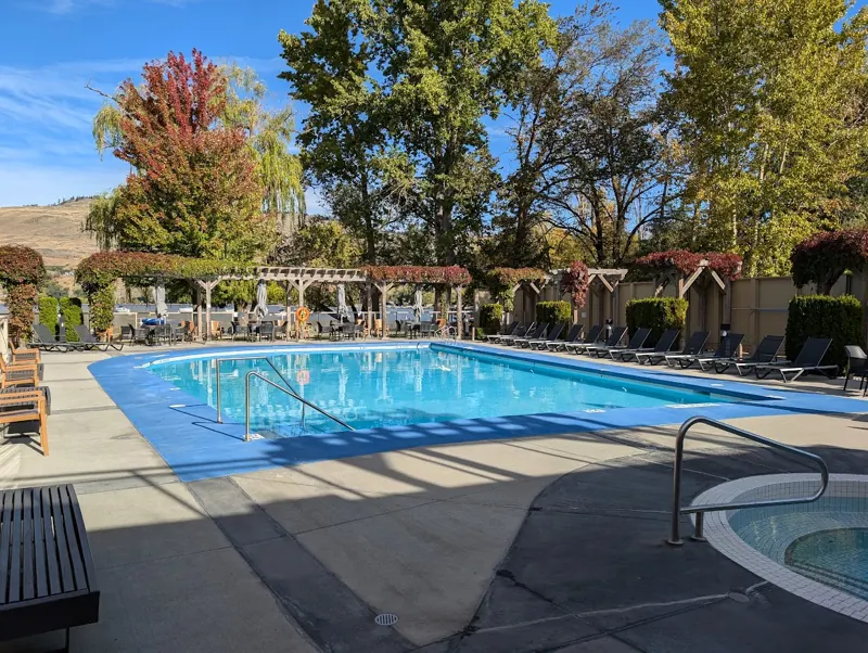 Heated outdoor pool at The Strand with fall colours and the hot tub